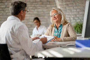 Happy mature woman having consultations with her doctor and talking about medical insurance possibilities at clinic.
