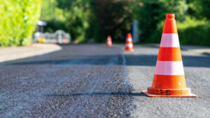 Construction cones marking part of road with a layer of fresh asphalt.