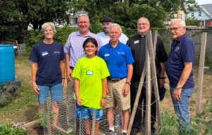 Sen. Yaw, Secretary Russell Redding and Several people pose together for a group photo inside a community garden, standing behind a small fenced-in plant bed.