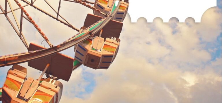 A close-up view of a Ferris wheel shows several gondola cars against a cloudy sky.