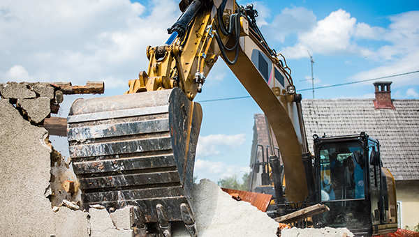 Mechanical digger demolishing building.